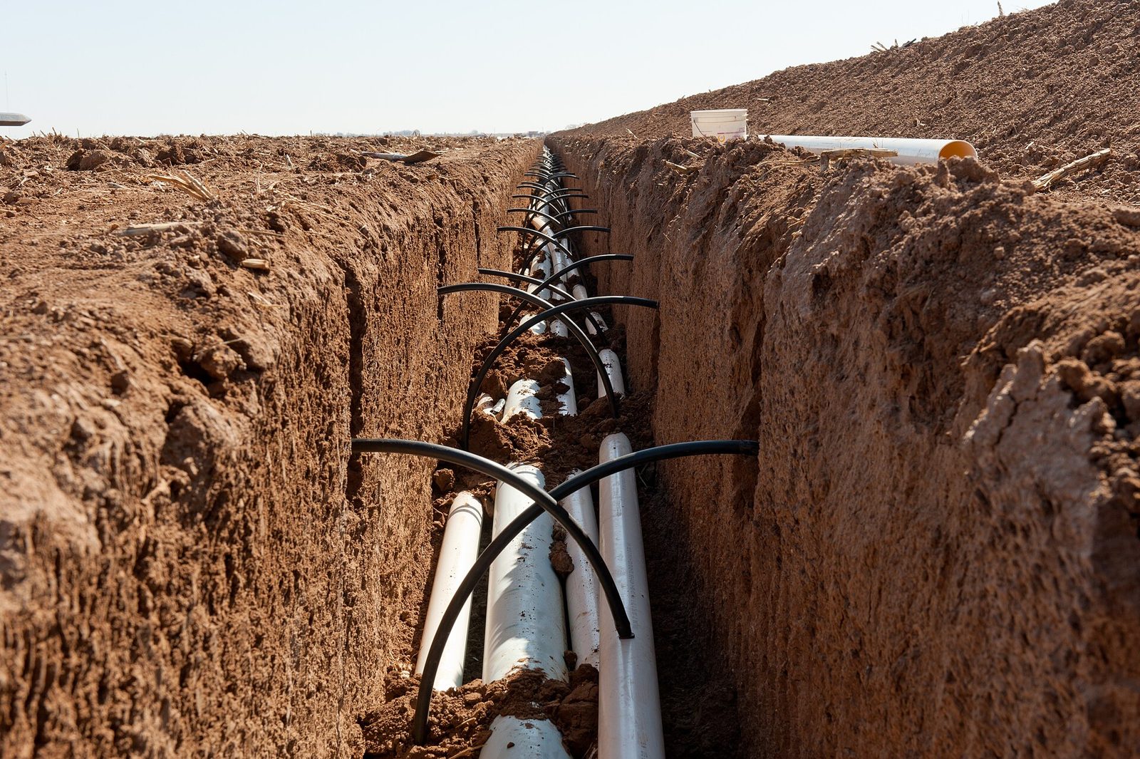 An open irrigation valve box in a lawn with the valves and wiring visible